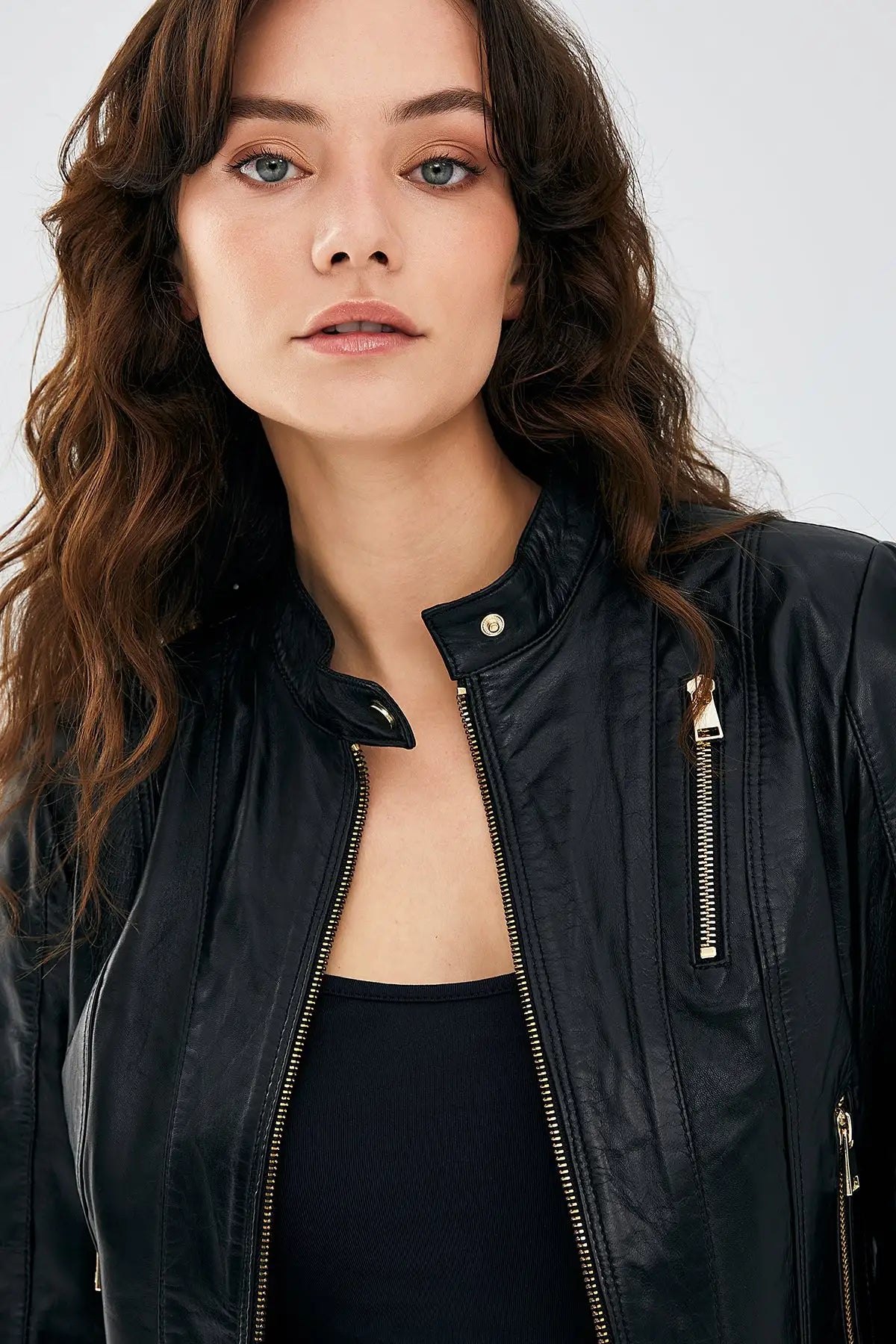 Close-up of solid brass hardware and diagonal seam paneling on women's leather biker jacket