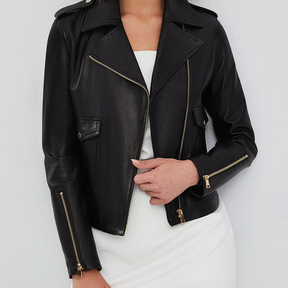 Close-up of the gold-tone zippered cuff hardware on the women's black asymmetrical biker leather jacket, showing the tapered sleeve seam.