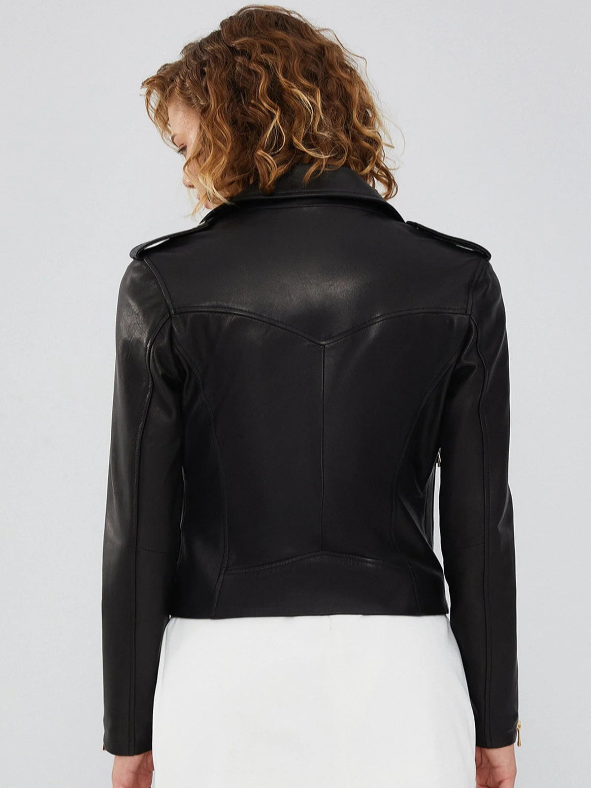 Back view of the women's black asymmetrical biker leather jacket, showing the princess-seamed panel and tailored, waist-nipping silhouette.