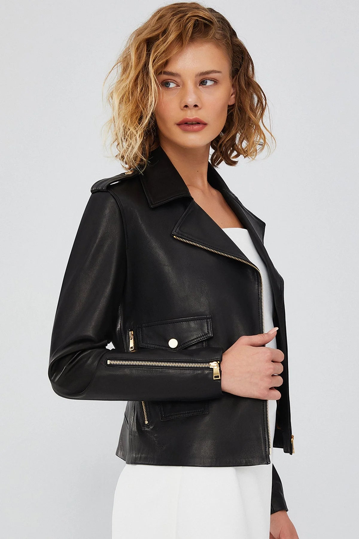 Left side profile of the women's black asymmetrical biker leather jacket, highlighting the shoulder epaulette and diagonal zip line.